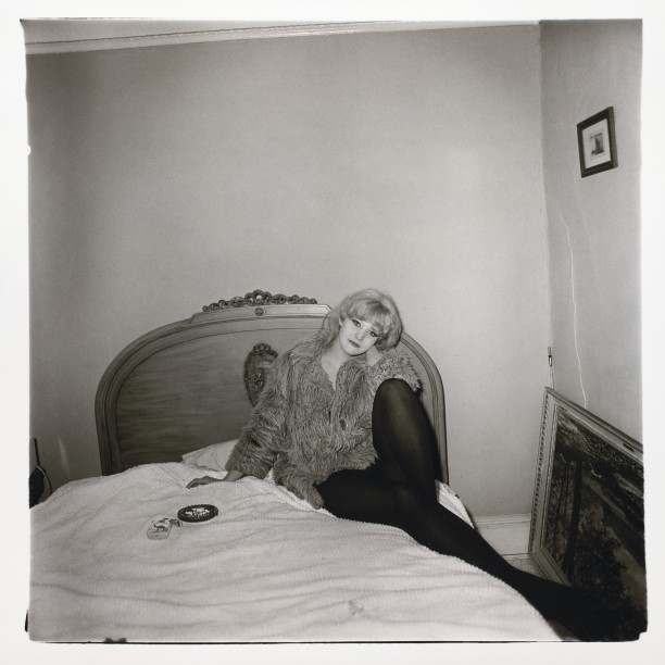 Girl in a coat lying on her bed, N.Y.C.