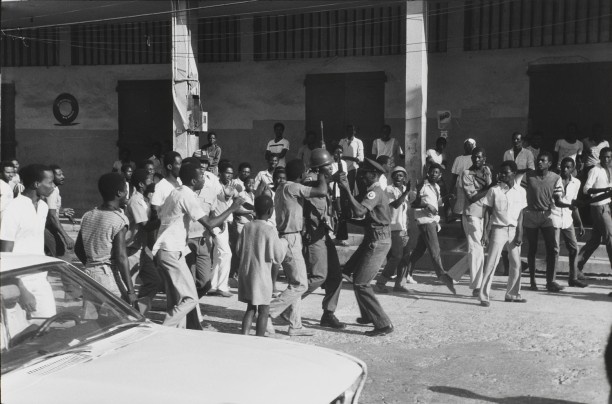 Dawn on February 7th. As news spreads that Jean-Claude Duvalier is gone, a soldier disarms a Tonton Macoute