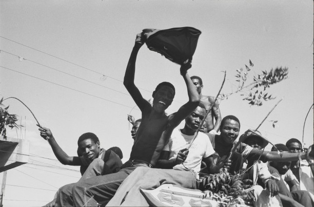 February 7th, Port-au-Prince. Students wave green branches and pieces of uniforms torn from the Tontons Macoute as they enter the capitol on a tap-tap